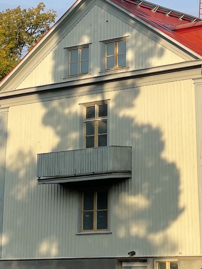 Nymålad ljusgrön trävilla med balkong och rött tak